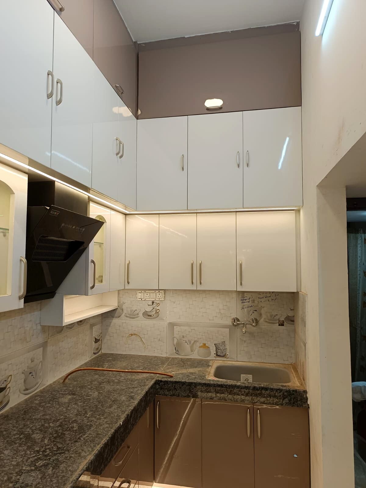 Compact kitchen with white upper cabinets and under-cabinet lighting